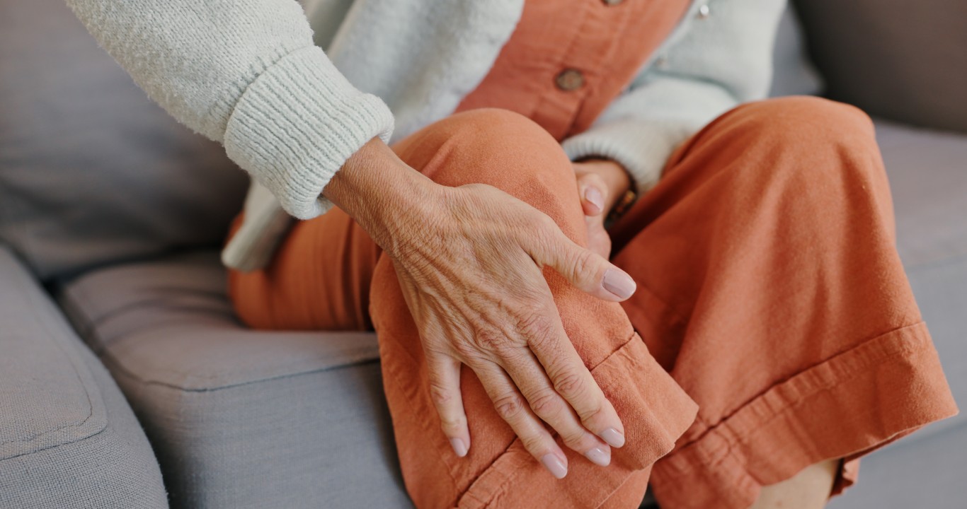 An elderly woman massages her knees to soothe pain from arthritis